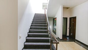 A staircase with a handrail leading to a landing. - Fabhotel Citi Inn (Dera Bassi)