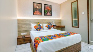 A modern bedroom with a large bed, two nightstands, a wooden headboard, and two framed pictures on the wall. - Fabexpress The Dream Residency (Mumbai)