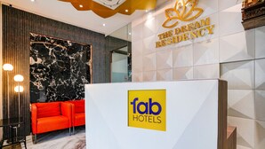 A reception area with a modern design, including a marble wall, a red sofa, and a reception desk with the 'fab hotels' logo. - Fabexpress The Dream Residency (Mumbai)