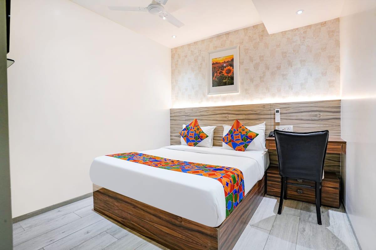 A modern bedroom with a wooden bed frame, a desk, and a chair.