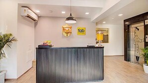 A reception desk with a modern design, a logo for 'Tab Hotels', and a decorative wall piece. - Fabhotel Ashray Residency (Navi Mumbai)
