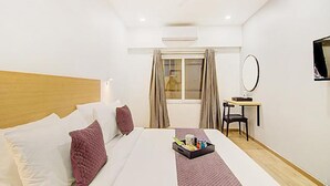 A hotel room with a bed, a desk with a chair, a window with curtains, and a TV on the wall. - Fabhotel Ashray Residency (Navi Mumbai)