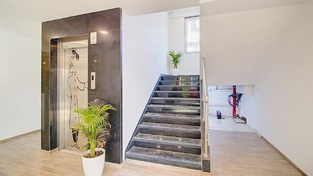 A modern interior with a staircase, a potted plant, and a minimalist design. - Fabhotel Ashray Residency (Navi Mumbai)