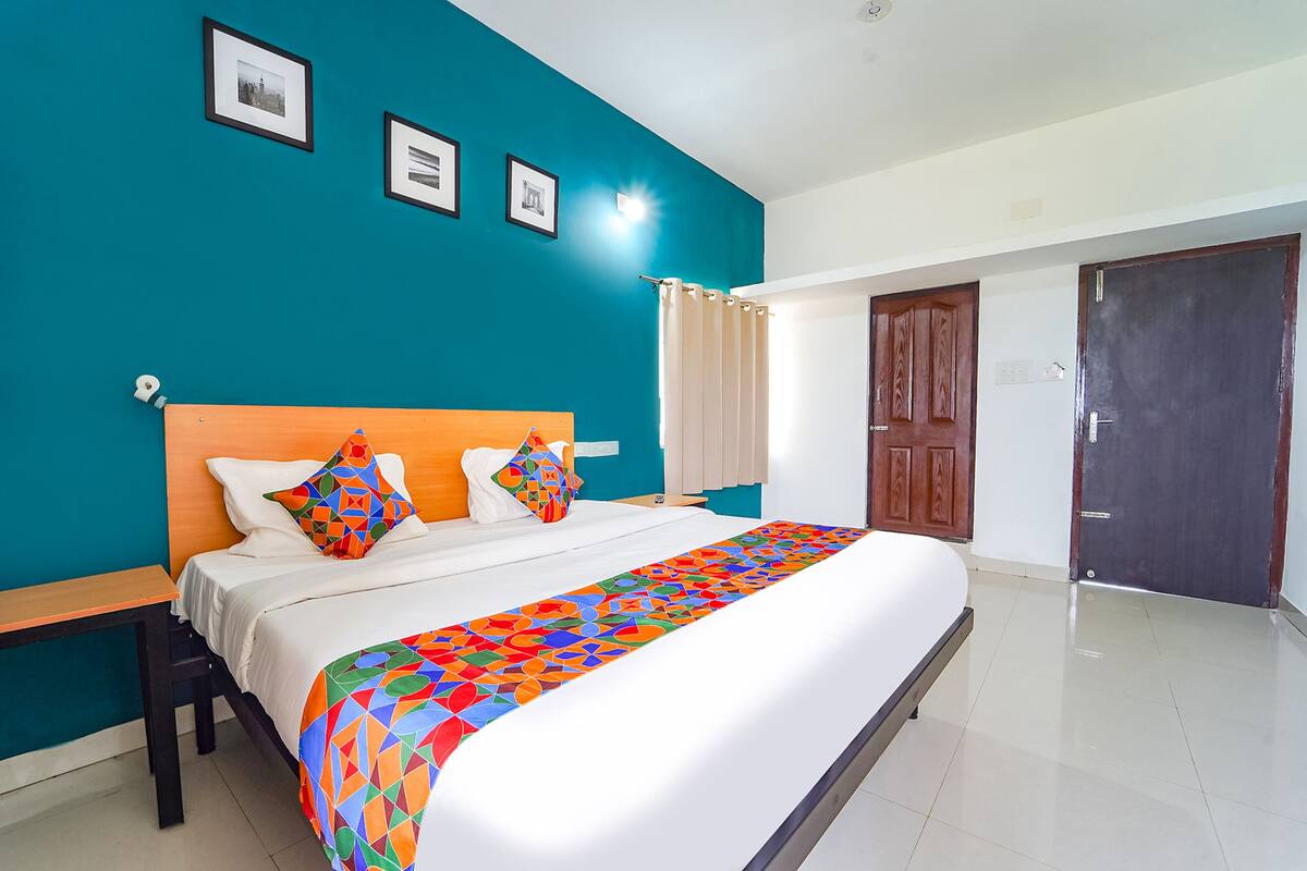 A hotel room with a large bed, a wooden headboard, and a teal accent wall.