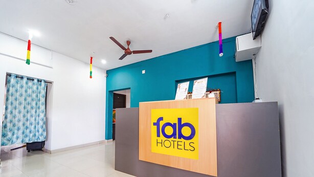 A reception desk with a 'fab hotels' sign, a ceiling fan, and a TV mounted on the wall. - FabHotel Virksham Thrivyn (Coimbatore)