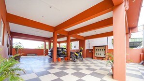 A covered parking area with a checkered floor, orange pillars, and potted plants. - FabHotel Virksham Thrivyn (Coimbatore)