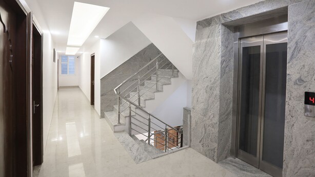 A modern hotel lobby with a marble staircase, an elevator, and a clean, polished floor. - FabHotel Taj Residency (New Delhi)