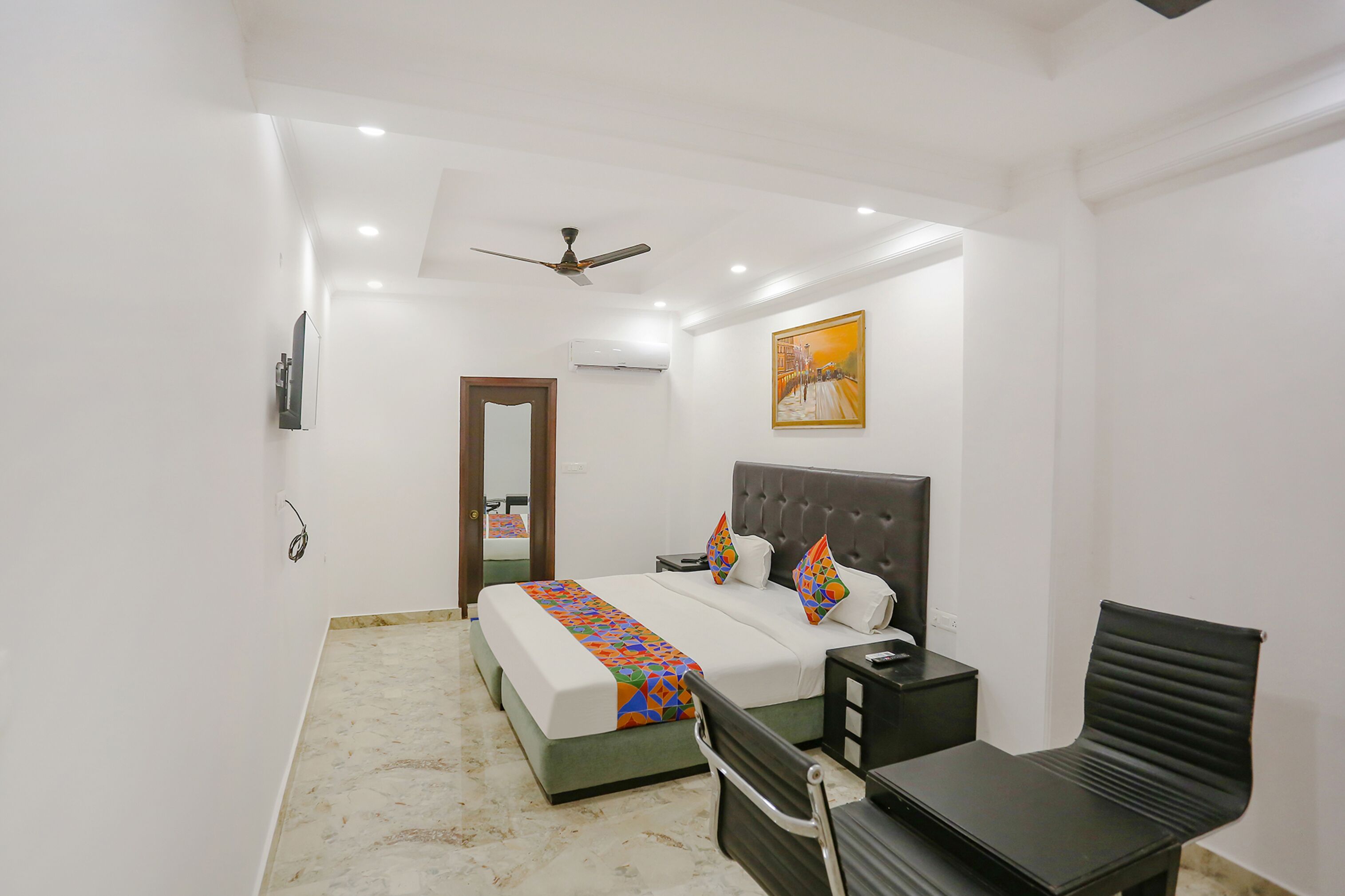 A bedroom with a bed, bedside table, chair, and a ceiling fan.