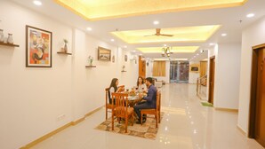 A dining area with a table set for four, a ceiling fan, recessed lighting, and a hallway leading to a staircase. - FabHotel Taj Residency (New Delhi)