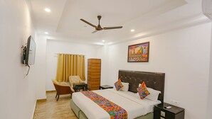 A hotel room with a bed, a chair, a nightstand, a television, and a painting on the wall. - FabHotel Taj Residency (New Delhi)