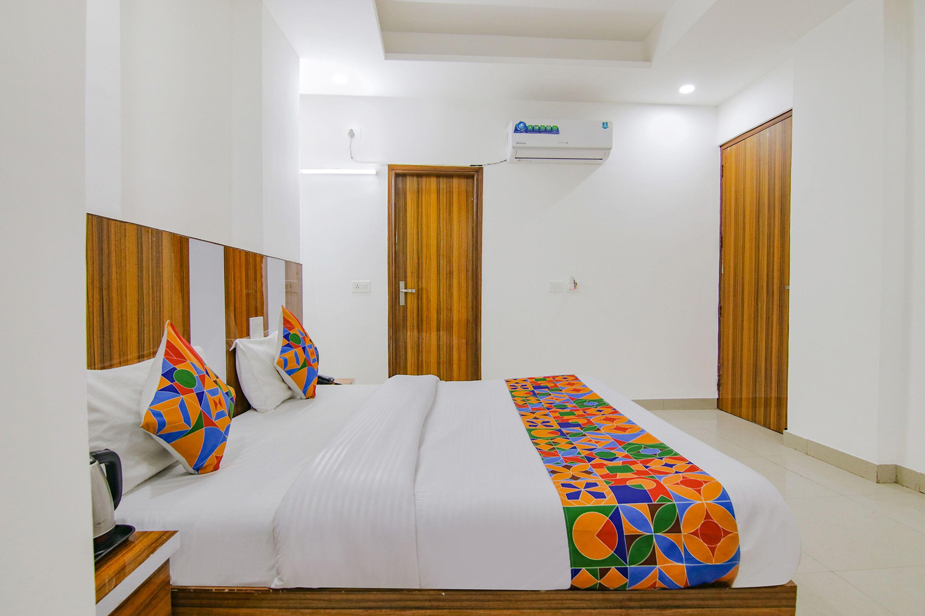 Habitación de hotel con cama, armario de madera, espejo del armario y equipo de aire acondicionado.