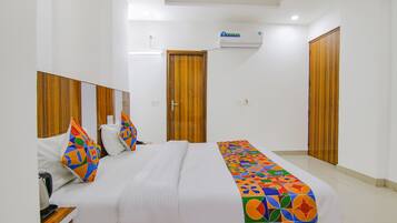 Habitación de hotel con cama, armario de madera, espejo del armario y equipo de aire acondicionado.