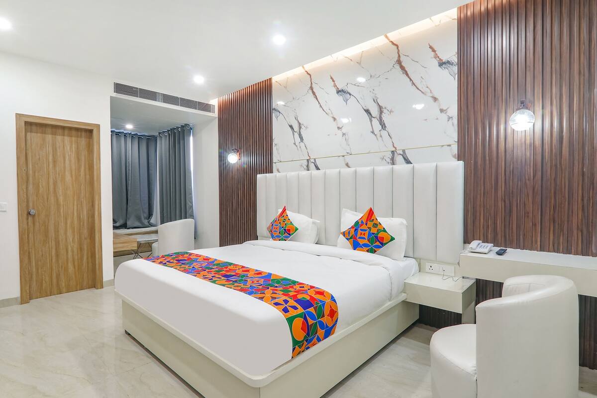 A modern bedroom with a bed, bedside table, and a mirror.