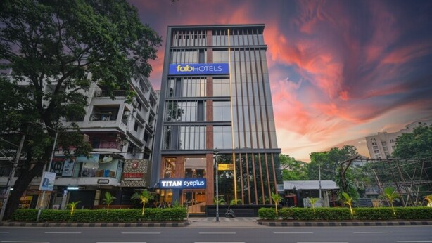 Un hôtel moderne, reconnaissable à son enseigne « fabHOTELS », abritant un magasin « TITAN eyeplus », et situé dans une rue urbaine bien entretenue.