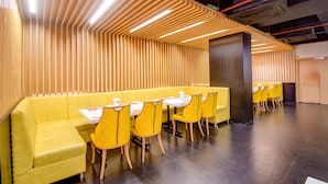 Un restaurant moderne avec des banquettes jaunes et un plafond en lambris de bois.