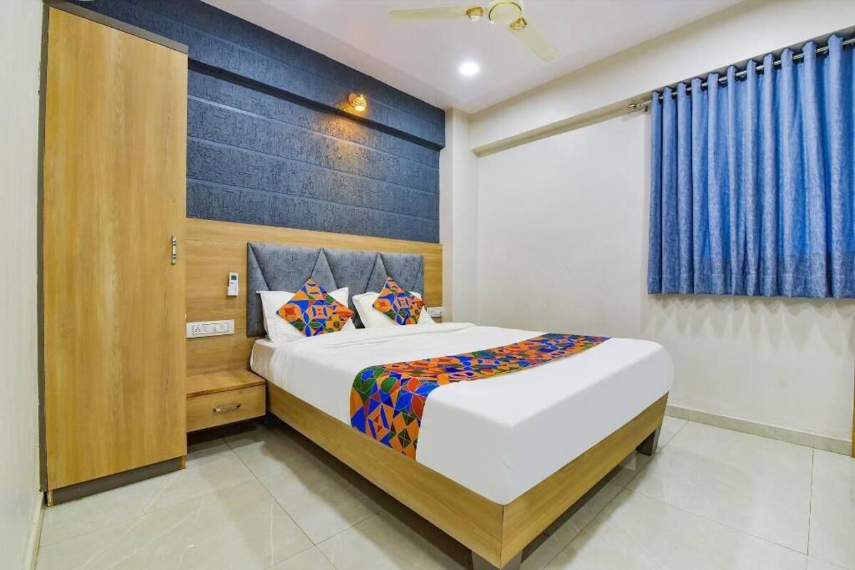 A bedroom with a bed, wooden wardrobe, and a ceiling fan.