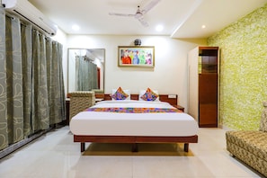 A bedroom with a bed, a ceiling fan, a wardrobe, a mirror, and a painting on the wall.