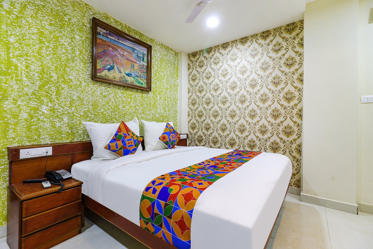 Una habitación de hotel con una cama, una mesita de noche, un teléfono y un cuadro en la pared.