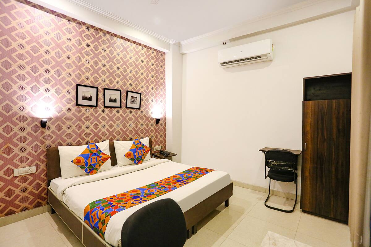 A neatly arranged bedroom with a bed, bedside lamps, a wall-mounted air conditioner, and a door.