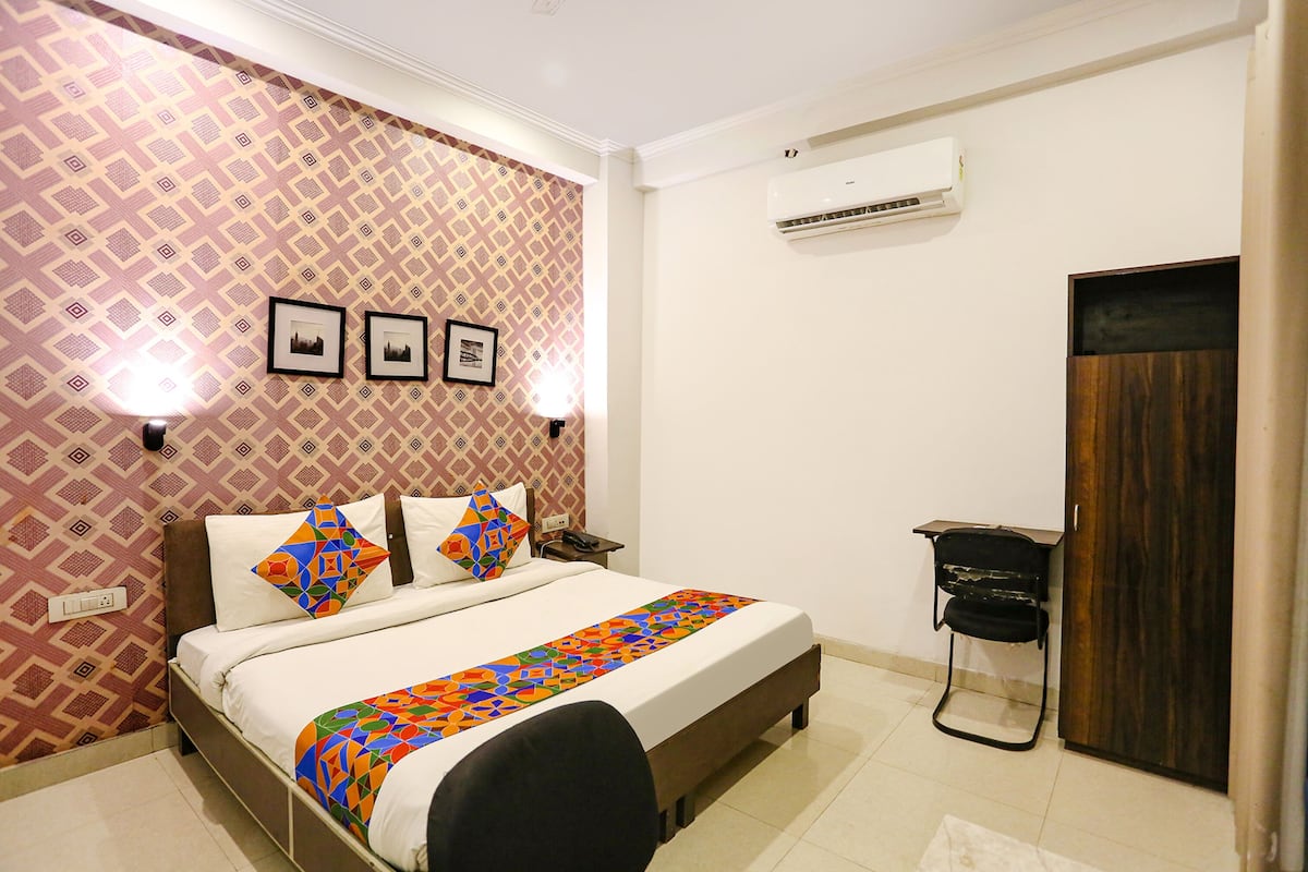 A neatly arranged bedroom with a bed, bedside lamps, a wall-mounted air conditioner, and a door.