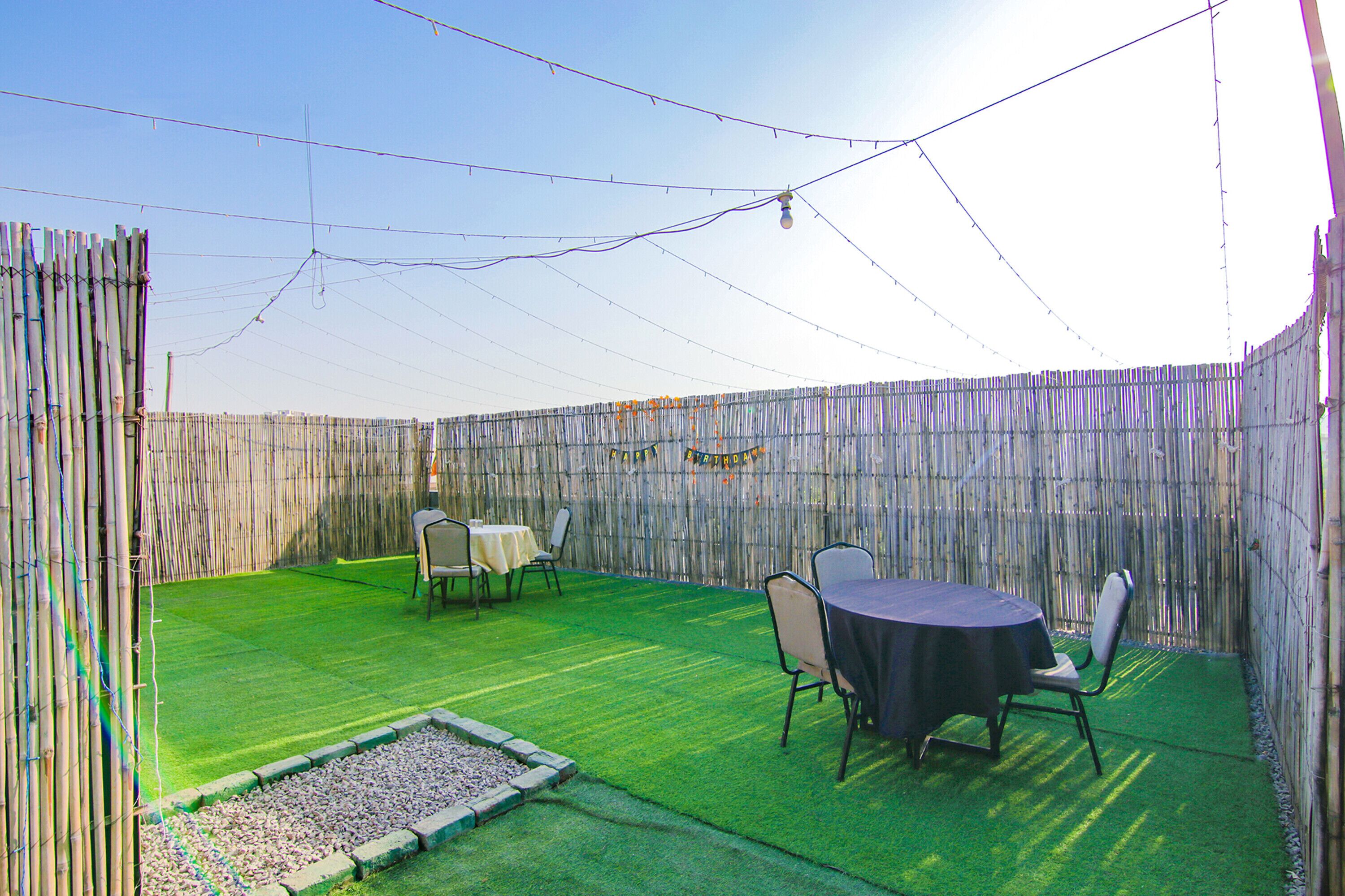 An outdoor patio area with a wooden fence, a table with chairs, and a string of lights.