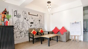 A modern office space with a minimalist design, featuring a sofa, a coffee table, and a whiteboard with writing. - FabHotel Infinity Stays (Gurugram)
