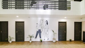 A spacious lobby with a high ceiling, a central mural, and multiple doors. - FabHotel Infinity Stays (Gurugram)