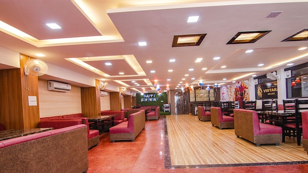Un restaurante con cabinas y mesas, un letrero de 'Feliz Cumpleaños' y un letrero de 'Hotel Vista Grand'.