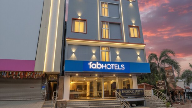Um edifício moderno com a placa 'fabhotels', apresentando uma entrada destacada e uma escadaria que leva à entrada principal.