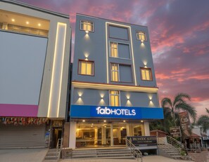 Un edificio moderno con el letrero 'fabhotels', que presenta una entrada destacada y una escalera que lleva a la entrada principal.