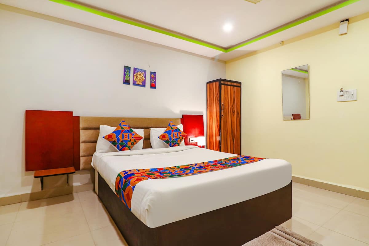 Habitación de hotel con una cama, una mesita de noche, un espejo y una pared con tres cuadros enmarcados.