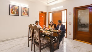A dining room with a marble floor, wooden chairs, a table set for four, and two framed artworks on the wall. - FabHotel Golden Gate - Hitech City (Hyderabad)