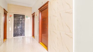 A hallway with marble walls and floors, two elevators, and a door marked with the number 4. - FabHotel Golden Gate - Hitech City (Hyderabad)