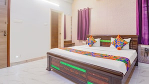 A bedroom with a large bed, a wooden headboard, and purple curtains. - FabHotel Golden Gate - Hitech City (Hyderabad)