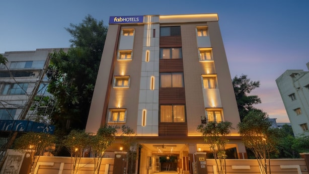 A modern building with a sign reading "fabHOTELS" at the top. It features a central entrance with a covered walkway and is surrounded by trees and other buildings. - FabHotel Golden Gate - Hitech City (Hyderabad)