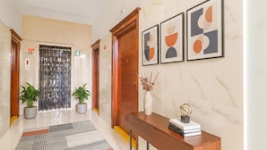 A modern hallway with a marble floor, a wooden reception desk, and framed abstract art on the wall. - FabHotel Golden Gate - Hitech City (Hyderabad)