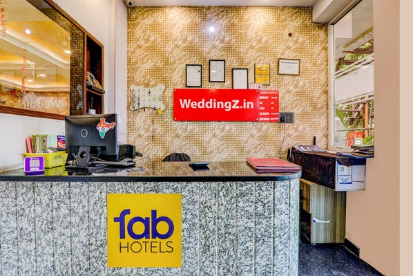 Una recepción de hotel con mostrador de mármol, una computadora y un cartel que dice 'fab hotels'.