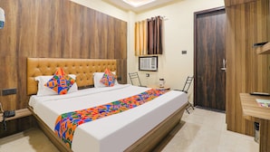 Une chambre d’hôtel avec un grand lit, une tête de lit en bois, une table de chevet avec une lampe et une armoire.