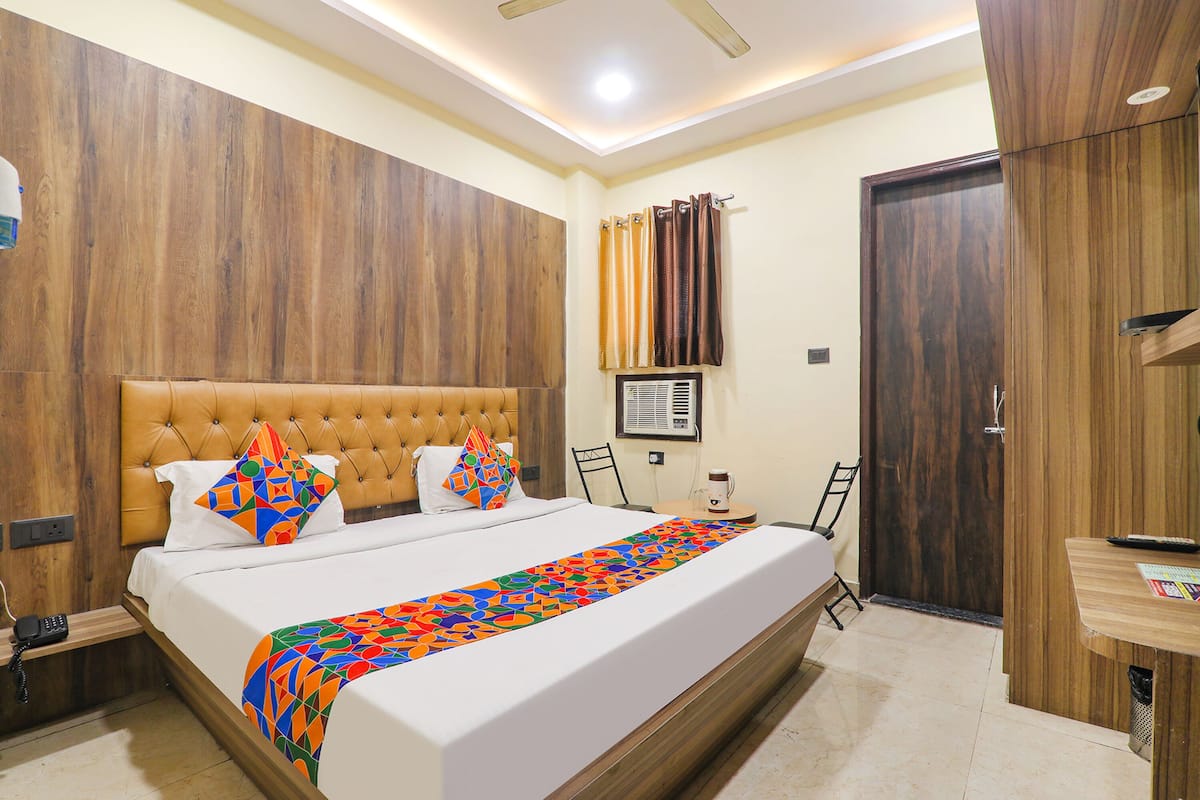 Una habitación de hotel con una cama grande, un cabecero de madera, una mesita de noche con lámpara y un armario.