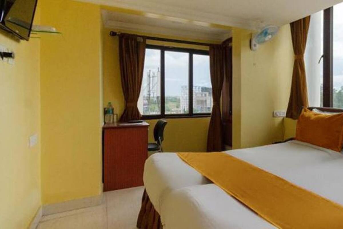 A hotel room with a bed, a desk, a chair, and a window with curtains.