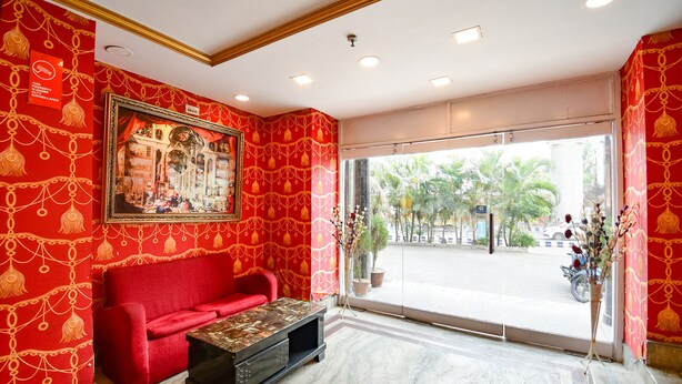Un vestíbulo de hotel con una pared de diseño rojo, un sofá rojo, una mesa de centro de madera y una gran foto enmarcada.