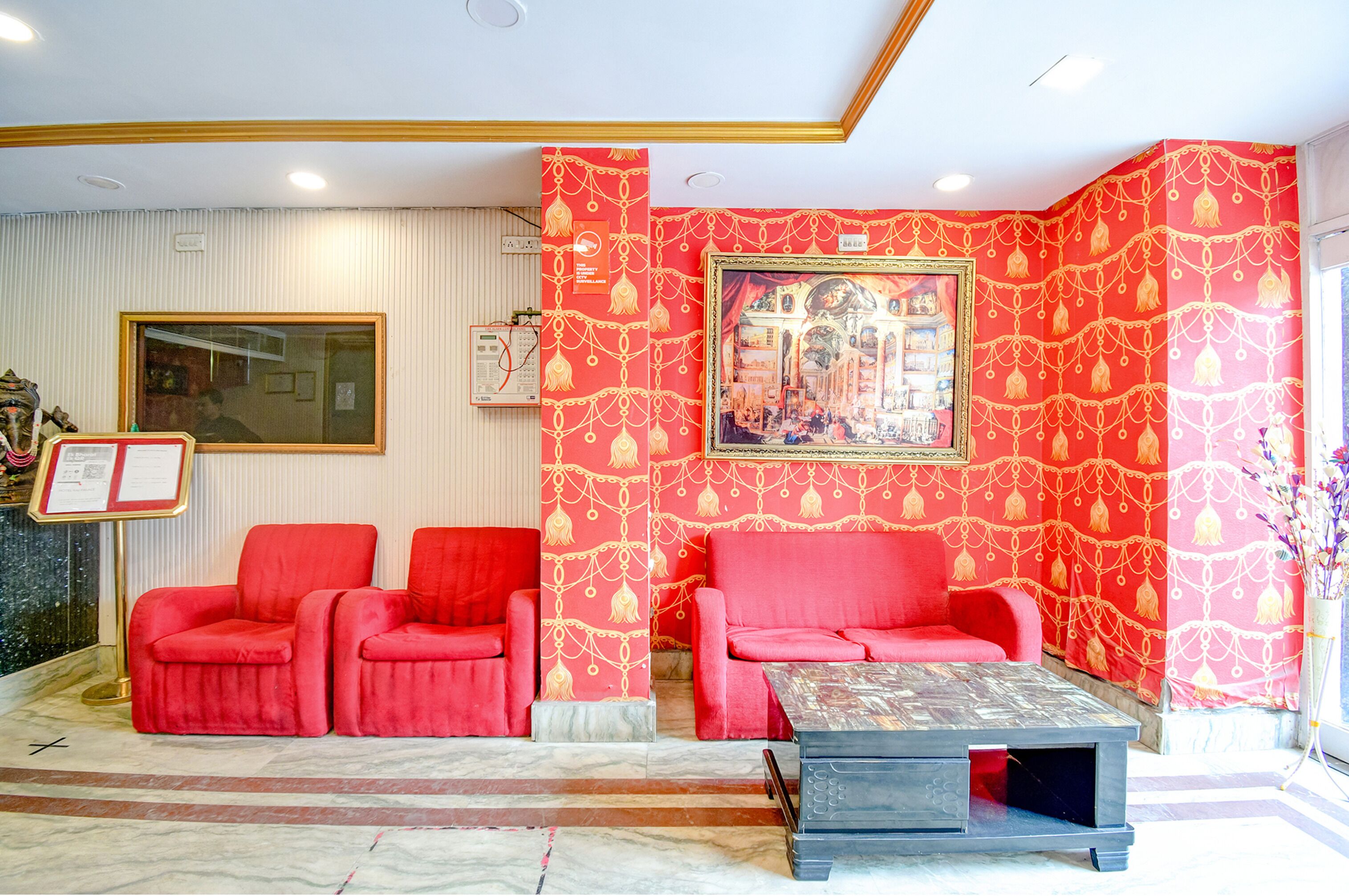A lobby with red seating, a framed artwork, and a reception desk.