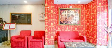 A lobby with red seating, a framed artwork, and a reception desk.