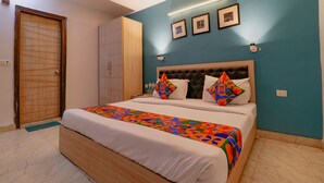 Un dormitorio con una cama grande, un armario de madera y una pared azul con cuadros.