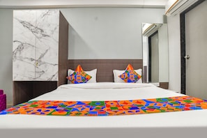 A hotel room with a large bed, a marble wall, and a mirror.