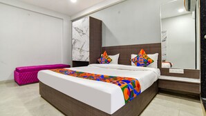 Een moderne slaapkamer met een groot bed, een roze bankje en een marmeren wand.