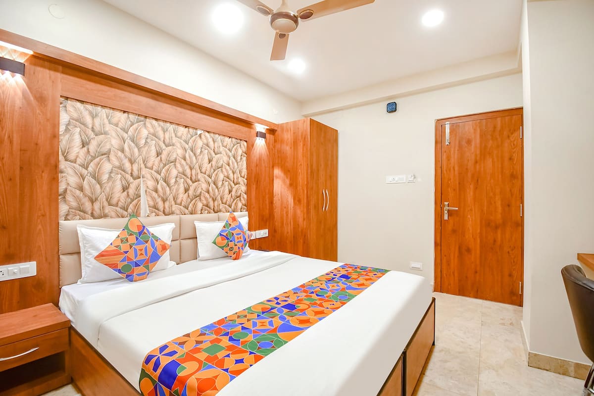 A bedroom with a bed, wooden wardrobe, and a ceiling fan.