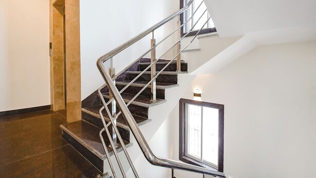 A staircase with metal railings, dark steps, and a light wall. - FabHotel Dreamworld Residency (Barasat)