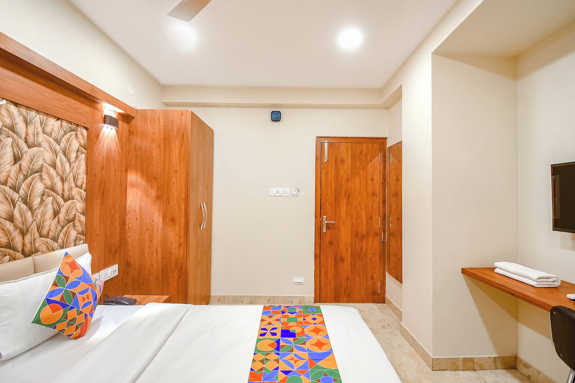 A hotel room with a bed, a desk, and two wardrobes.