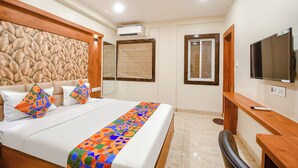 A hotel room with a bed, a desk, a TV, and a ceiling fan. - FabHotel Dreamworld Residency (Barasat)